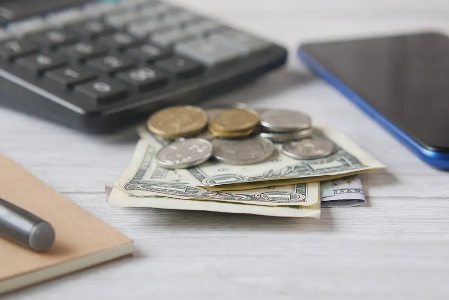 Desk with laptop, calculator and coins, representing IT and technology finance